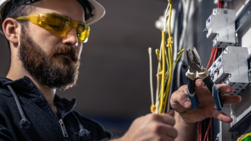 male-electrician-works-switchboard-with-electrical-connecting-cable_169016-15085